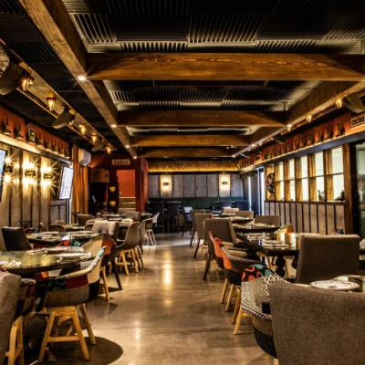 Vista del interior del restaurante Cometa, con un ambiente moderno y cálido, mesas vestidas y sillas coloridas bajo un techo de madera iluminado.