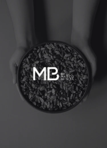 Cuenco con granos sostenido entre manos, con el logo de MB by Marco Beteta, guía gastronómica que reconoce la propuesta culinaria de KOLI.